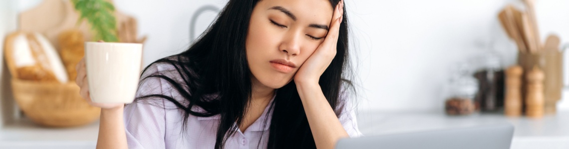 A woman falling asleep at her desk.