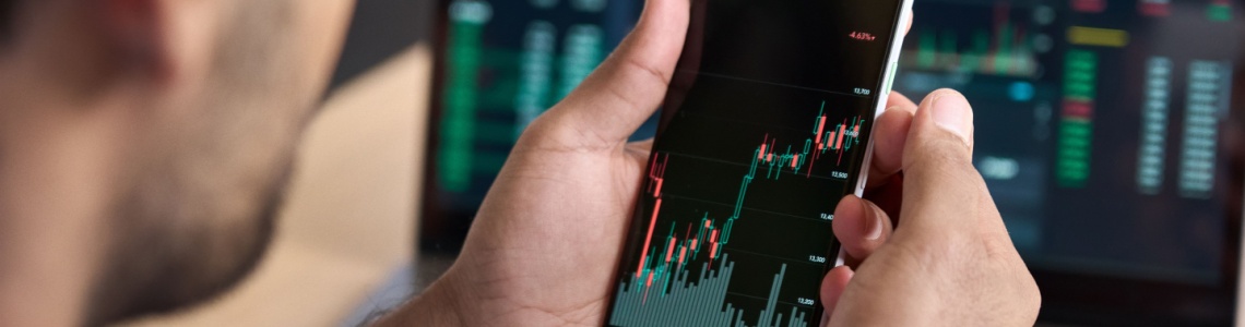 A man looking at a graph showing stock market performance on his phone.