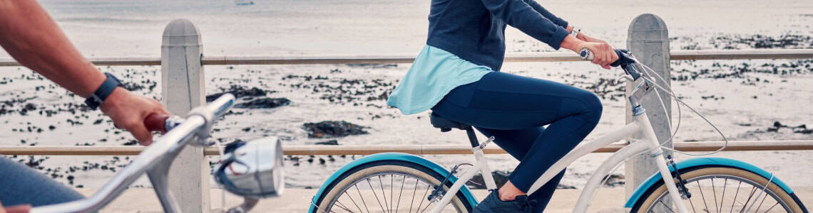 A woman cycling along a beachfront.