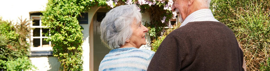 Rear view of senior couple outside pretty cottage